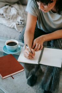 femme avec un café qui écrit sur une feuille